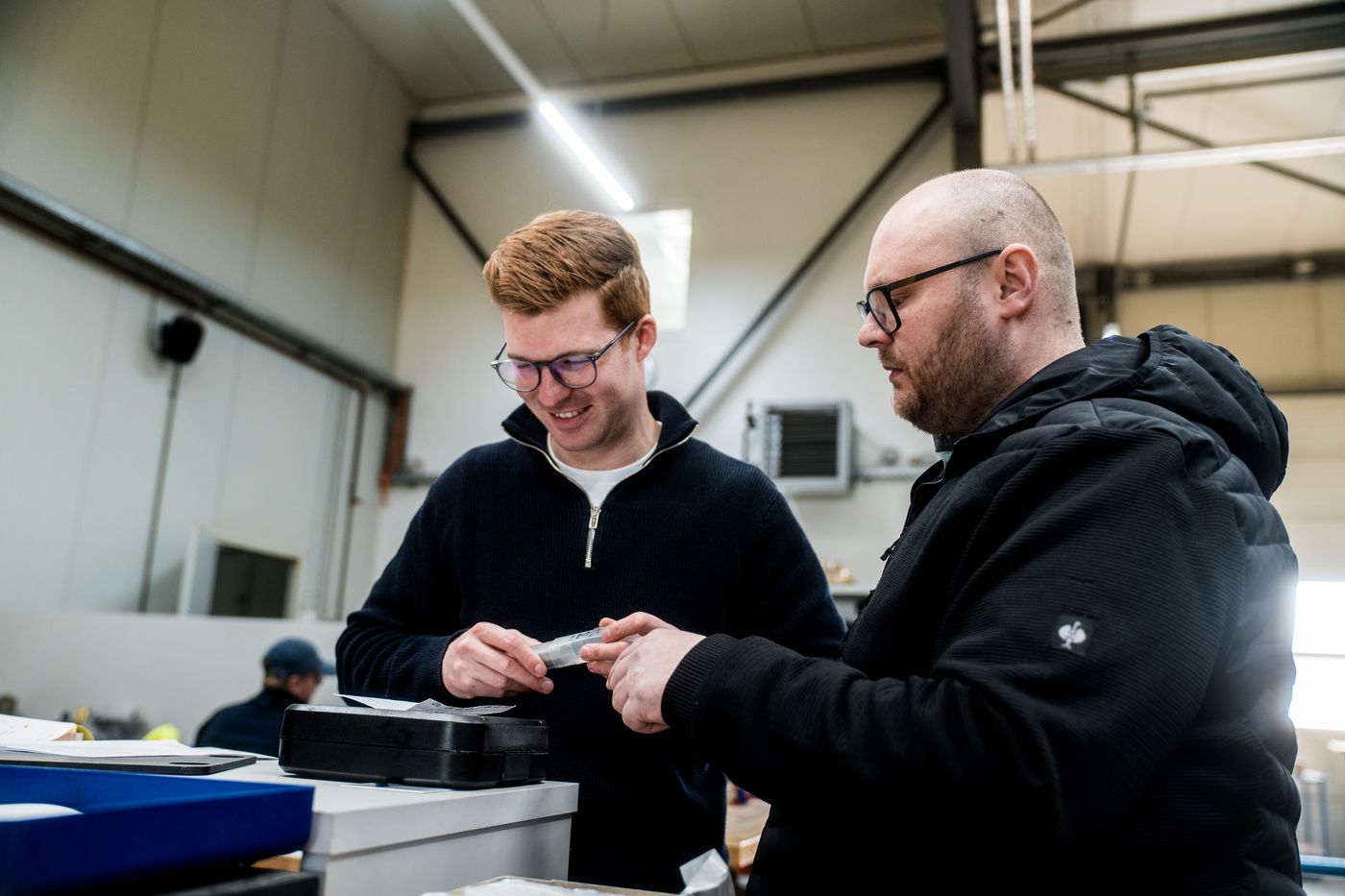 Zwei Mitarbeiter besprechen ein Werkzeug in der Werkstatt